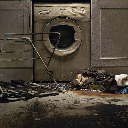 Fire damaged kitchen with washing machine and upturned clothes horse