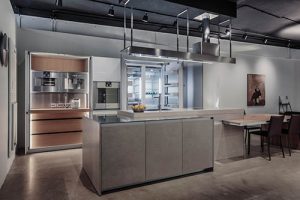 The Icon kitchen is a winner of a Red Dot Design award. This display has been finished with tall glass units, a porcelain island with stainless steel countertop and signature pullout retractable dining table in wood finish