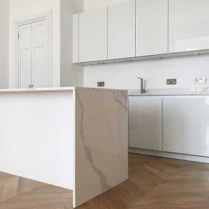 Störmer high-gloss lacquered white handleless cabinets finished with Calacatta quartz worktops and stainless steel accessories 